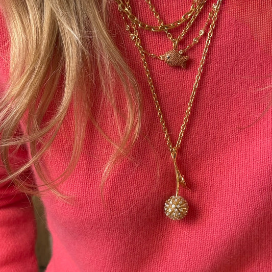 Gold necklace with a pendant on a pink background