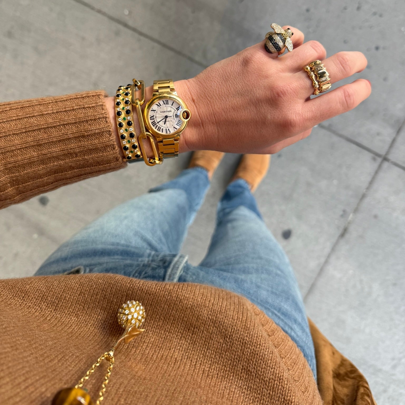 Hand wearing a gold watch and bracelets with a blurred background