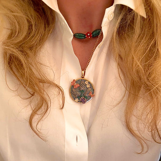 Necklace with a round pendant worn by a person in a white shirt