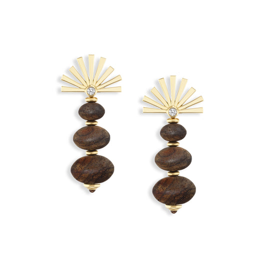 Pair of earrings with sun ray pattern in gold at the top and carved wooden beads on the dangle bottom, on a white background