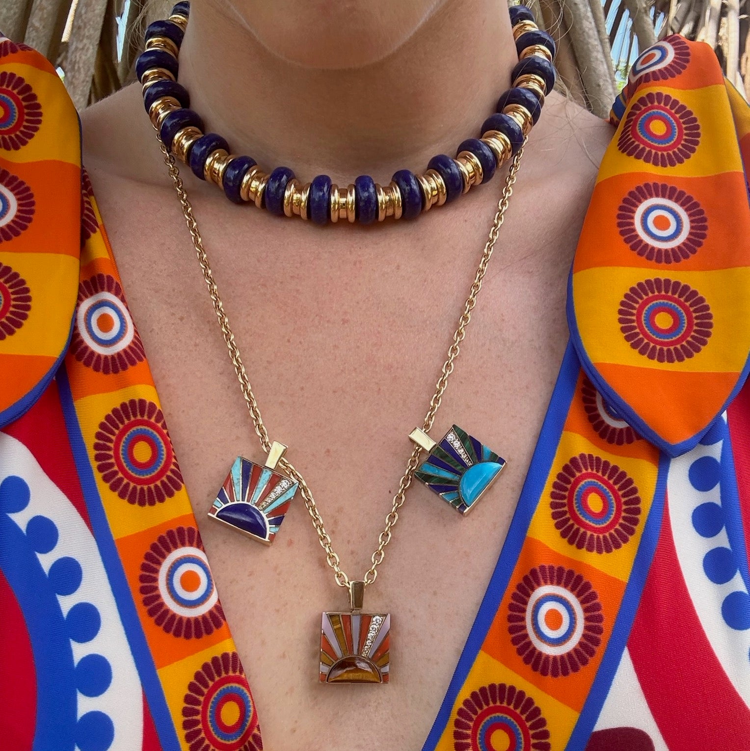Person wearing colorful necklaces with decorative pendants and a colorful garment.