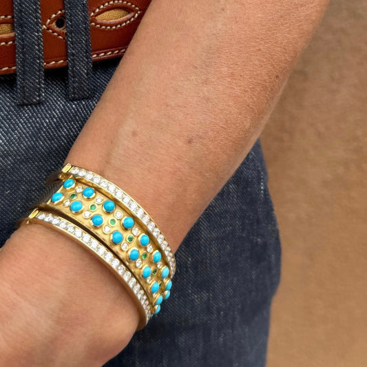 Gold bracelet with turquoise stones on a wrist against a denim background