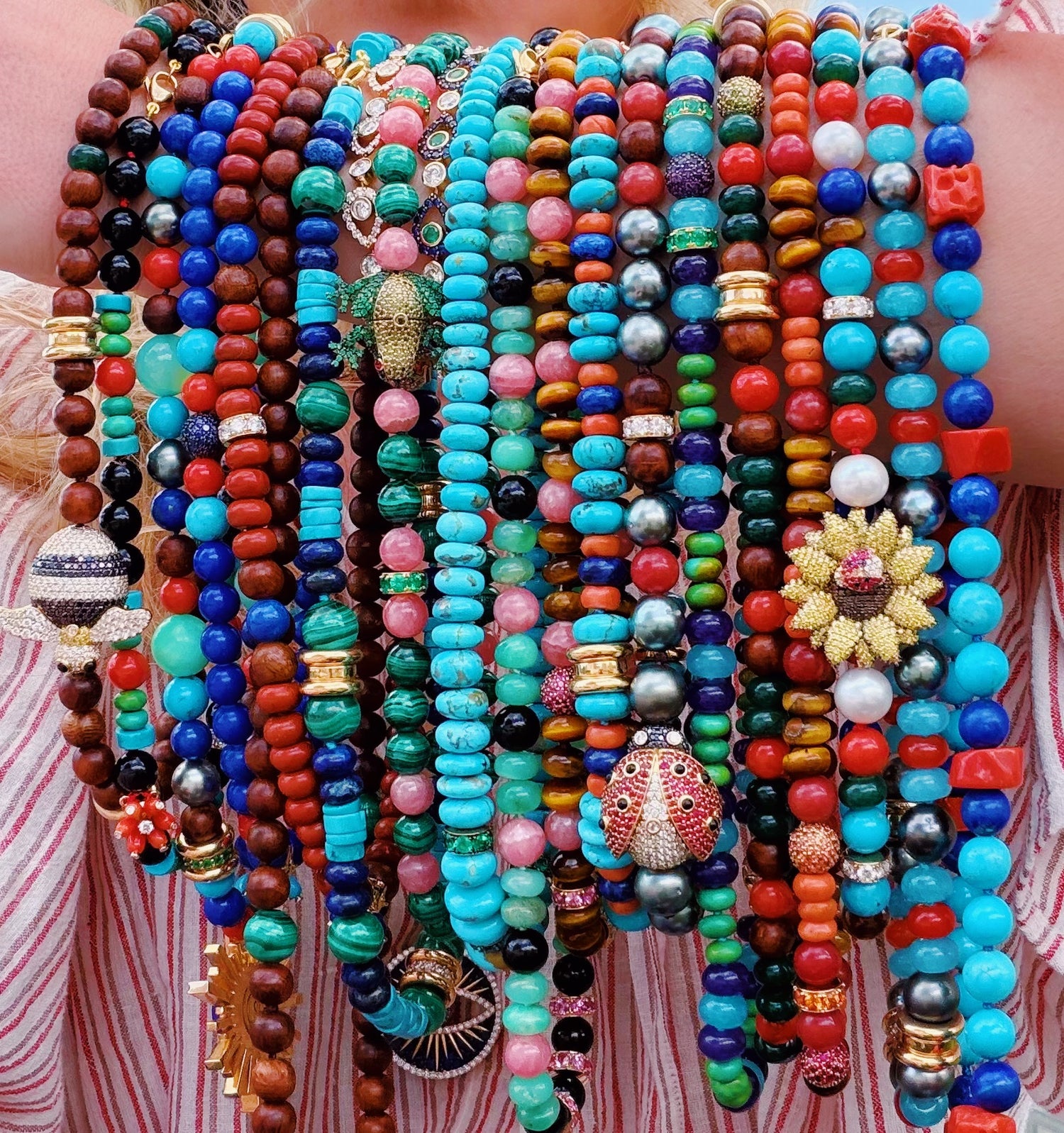 Colorful beaded bracelets on a person's wrist with a striped fabric background