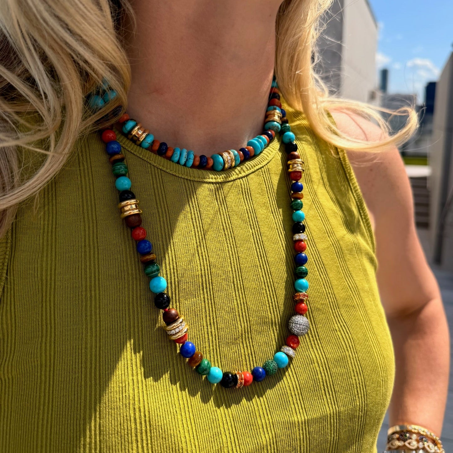 Colorful beaded necklace worn by a person with a blurred outdoor background