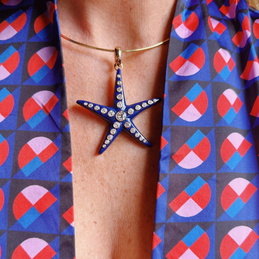 Starfish-shaped pendant on a person's neck with a colorful geometric-patterned shirt. 