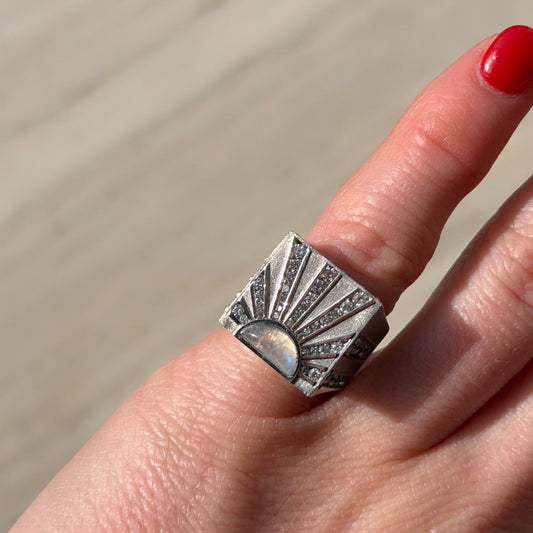 Silver ring on a finger with a neutral background