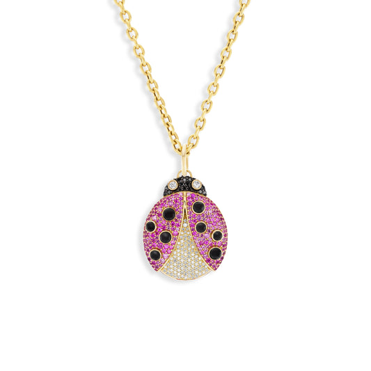 Gold necklace with a ladybug pendant featuring pink and black gemstones on a white background
