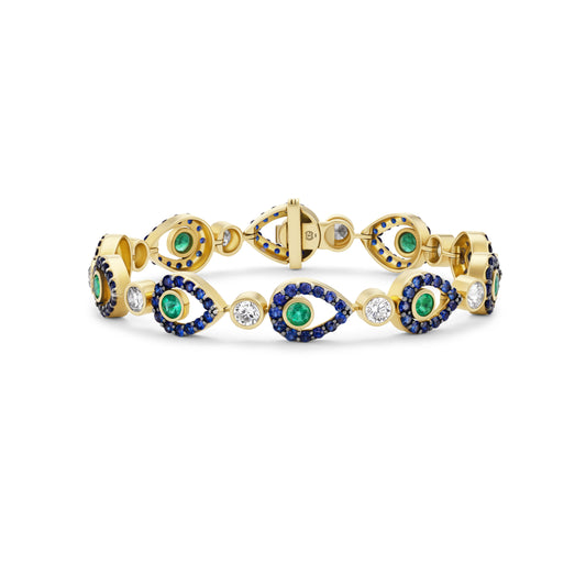 Gold bracelet with green and blue gemstones on a white background
