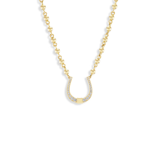 A delicate gold chain necklace featuring a horseshoe-shaped pendant adorned with small clear stones, set against a solid white background.