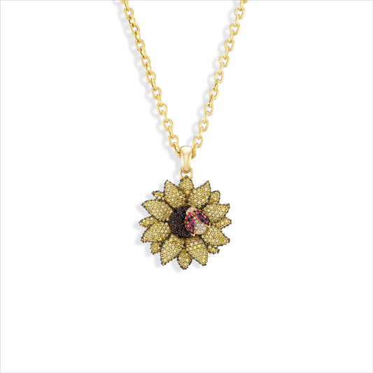 A gold chain necklace with a flower-shaped pendant featuring gold pavé-set petals, a dark brown center, and a small pink gemstone in the middle, shown on a plain white background.